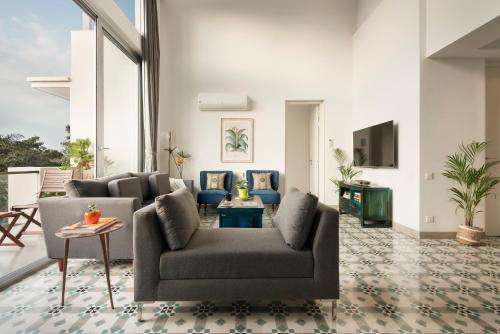 a living room with a couch and a tv at El Reino Elegant 2&3BHK Apartments 10 Minutes to Candolim with Pool & Kitchen, Wifi, Security in Verem