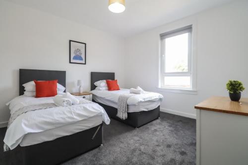 a bedroom with two beds and a window at The Cove Apartment in Gourock