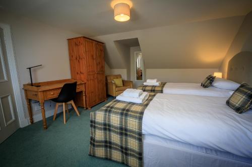 a hotel room with two beds and a desk at Cosy Cottage in Fishertown, Nairn - Free Parking & Pets welcome in Nairn