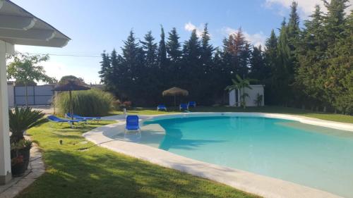 a large swimming pool in a yard with chairs and trees at Chalet Brisas del Mar in Chiclana de la Frontera