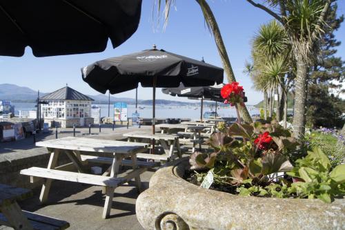 d'une terrasse avec des tables, des chaises et un parasol. dans l'établissement The Bulkeley Hotel, à Beaumaris