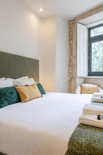 a bedroom with a large white bed and a window at ORM Carregal Apartment in Porto