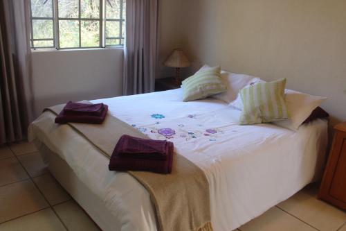 a white bed with pillows on it in a bedroom at Nature Cottage in Marloth Park