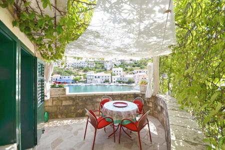 a table and chairs on a patio with a pool at Villa Povlja in Povlja