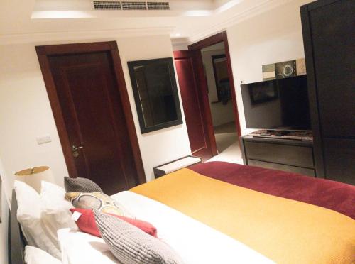 a hotel room with a bed and a television at Luxury 2 bedroom Apt in The Pearl with Marina view in Doha
