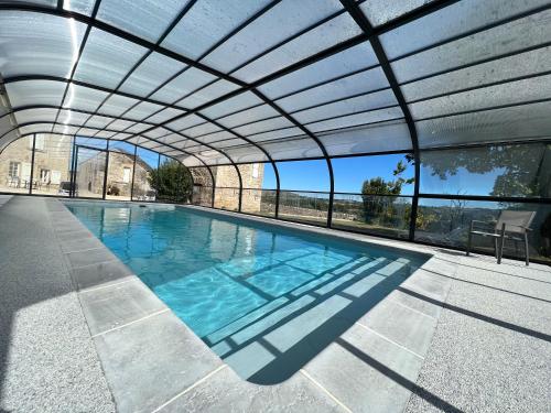 uma piscina interior com uma pérgola em Les Distinguées - Manoir de Bessodes em Recoules-Prévinquières