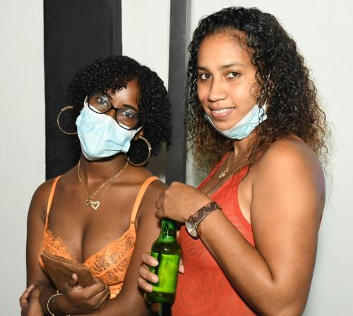 dos mujeres con máscaras y sosteniendo una botella de cerveza en Metro Hotel Couva, en Couva