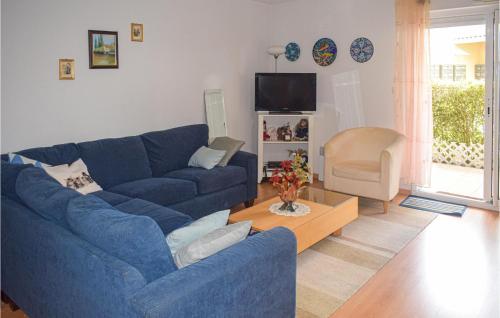 a living room with a blue couch and a table at Amazing Apartment In Vaux-Sur-Mer in Vaux-sur-Mer