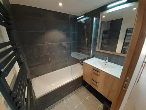 a bathroom with a sink and a tub and a mirror at Superbe appartement T3 4 étoiles terrasse accès spa in Saint-Chaffrey