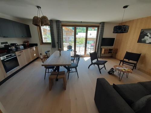 une cuisine et un salon avec une table et des chaises dans l'établissement Superbe appartement T3 4 étoiles terrasse accès spa, à Saint-Chaffrey