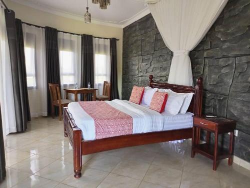 een slaapkamer met een bed en een stenen muur bij Nile Bridge Cottages in Jinja