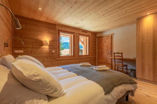 ein Schlafzimmer mit einem großen Bett mit Holzwänden und einem Fenster in der Unterkunft Chalet Les Bognettes 10 personnes in Le Grand-Bornand
