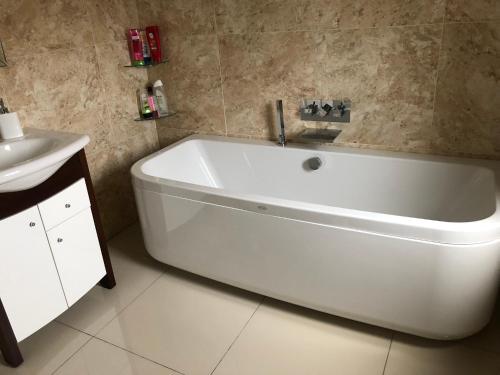 a white bath tub in a bathroom with a sink at Meadowview Cottage, Garden View in Camborne