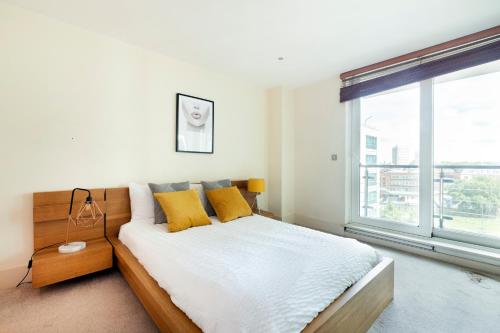 een slaapkamer met een bed met gele kussens en een raam bij Beautiful river view close to London Eye in Londen