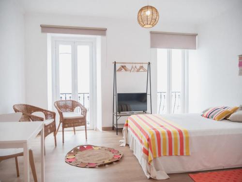 a white bedroom with a bed and a table and chairs at Alcácer Central Apartments in Alcácer do Sal