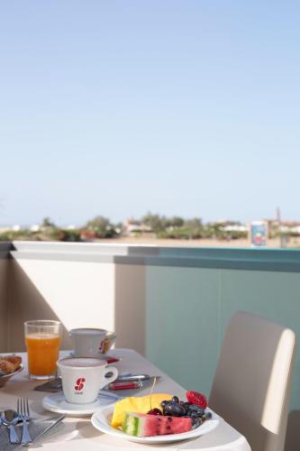 a table with a plate of fruit and a drink at Hotel Monaco in Caorle