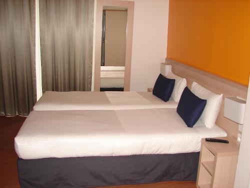 a bedroom with a large white bed with blue pillows at Budget Hotel Melun Sud - Dammarie Les Lys in Dammarie-lès-Lys
