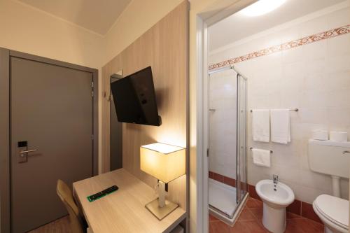a bathroom with a toilet and a tv on the wall at Hotel Monaco in Caorle