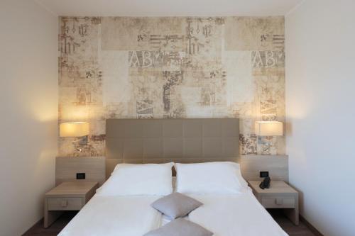 a bedroom with a large white bed with two tables at Hotel Monaco in Caorle