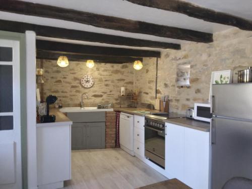 a kitchen with white appliances and a brick wall at Reids Retreat in La Roche-lʼAbeille