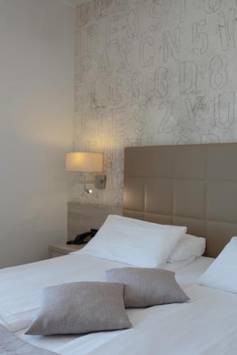 a bedroom with a white bed and a wall with letters at Hotel Monaco in Caorle