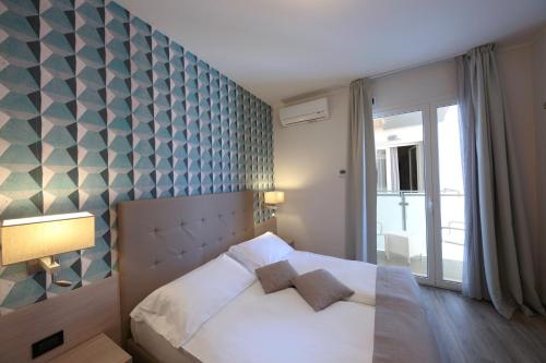 a bedroom with a white bed and a blue wall at Hotel Monaco in Caorle