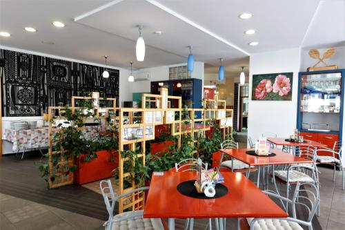 a restaurant with red tables and chairs and plants at Hostel Soline in Portorož