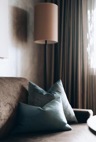 a lamp sitting next to a bed with pillows at Hotel Das Stachelburg in Parcines