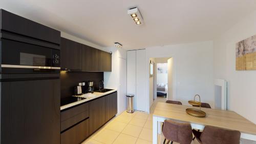 a kitchen with black cabinets and a table and chairs at Evancy Platier d'Oye - Oye-Plage in Oye-Plage