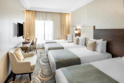 a hotel room with four beds and a desk at Millennium Makkah Al Naseem in Makkah