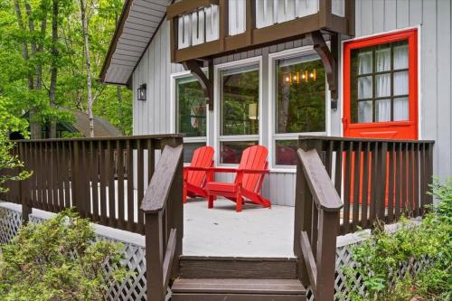 a porch with two red chairs on a house at The Gingerbread House: 4 BR chalet, w/ Sunroom/Deck, sleeps 12, modern amenities in McGaheysville