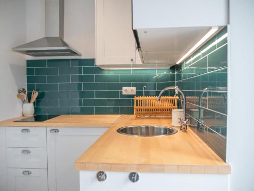 a kitchen with a sink and a green tiled wall at Alcácer Central Apartments in Alcácer do Sal