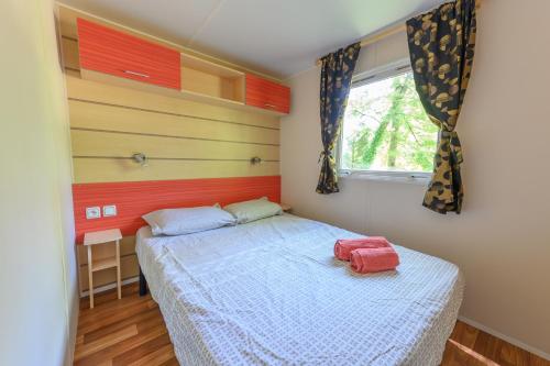 une chambre avec un lit et une fenêtre dans l'établissement Mobil-home LE WILSON, à Mirgaudon