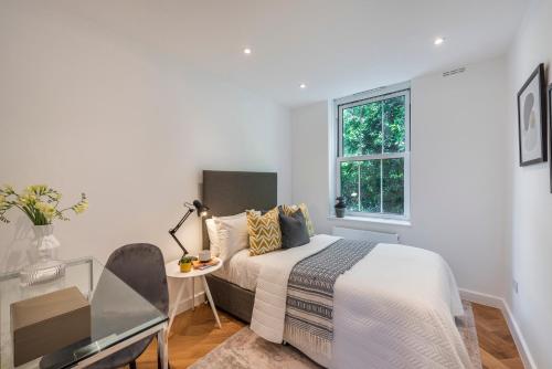 a bedroom with a bed and a table and a window at Superb 2 bed apartment near Camden Town FREE WIFI in London