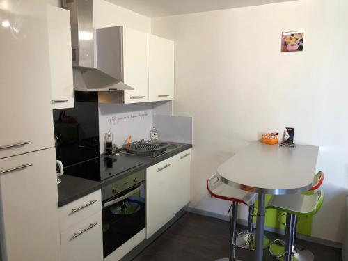 une cuisine avec des armoires blanches et une table à l'intérieur dans l'établissement Résidence Pierre François, à La Roche-sur-Yon