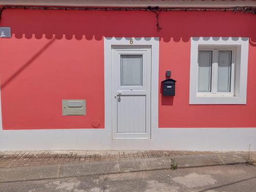 a red and white building with a door and a mailbox at Casa Coral in São Marcos do Campo