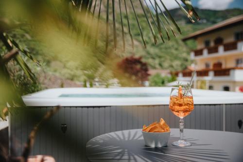 a glass of wine and chips on a table on a balcony at Hotel Bischofhof in Chiusa