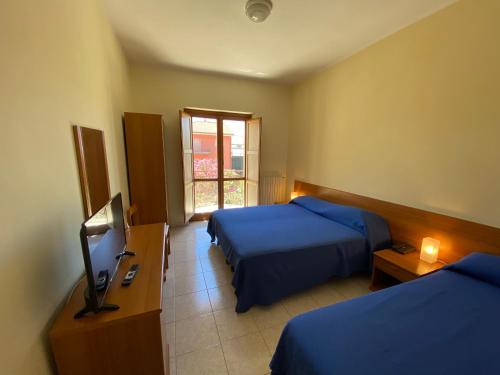 una camera d'albergo con due letti e una televisione di Hotel Mercure a Castelluccio Inferiore
