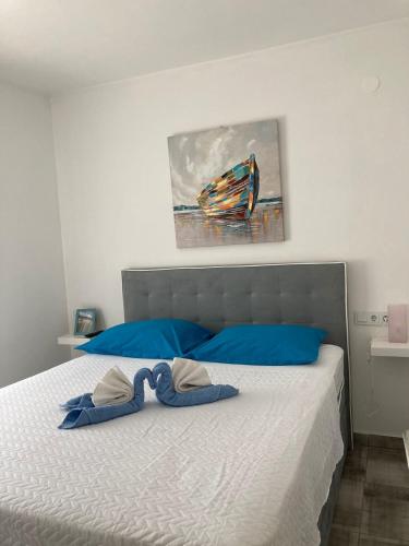 a bed with blue pillows and a painting on the wall at TAL in Tisno