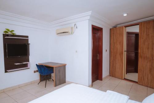 a bedroom with a bed and a desk and a tv at RESIDENCE OLIE OFFICIEL in Douala