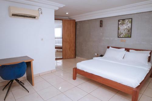 a bedroom with a white bed and a desk and a desk at RESIDENCE OLIE OFFICIEL in Douala