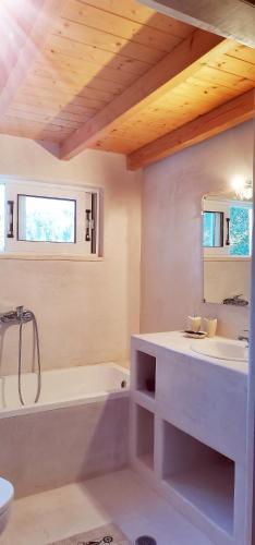 a white bathroom with a tub and a sink at Spiro's cottage by Alegria apartments in Vlachopoulátika