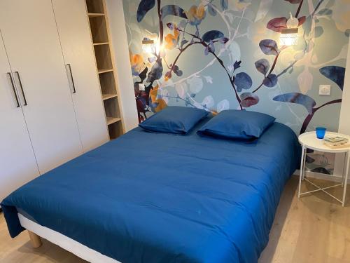 a bedroom with a blue bed with a tree mural at Ker Melen in Cléder