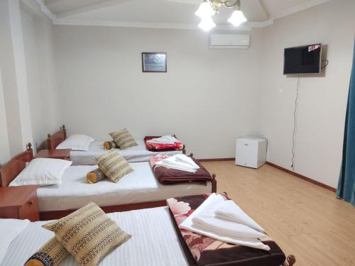 a room with four beds and a flat screen tv at Hotel Nazira & Azizbek in Bukhara