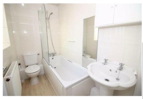 a white bathroom with a toilet and a sink at Cheerful 2 bedroom house in Hindley