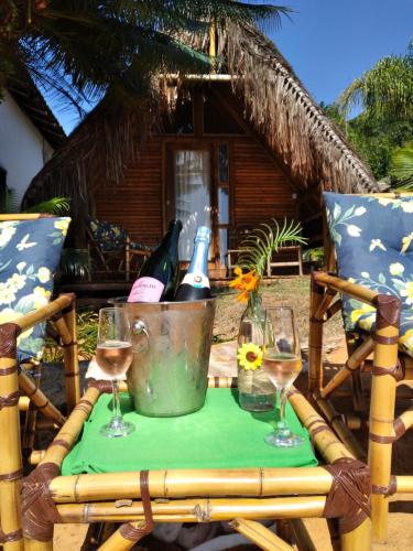 una mesa con copas de vino y un cubo de botellas de vino en Chalés do Pedro Hospedagem e Restaurante, en Praia de Araçatiba
