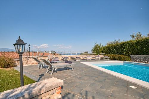 a swimming pool with lounge chairs and a light pole at Villa Ardea in Soiano del Lago