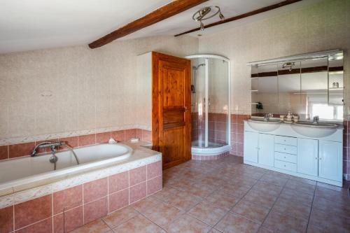 ein Bad mit einer Badewanne, einer Dusche und einem Waschbecken in der Unterkunft Villa Carpe Diem in Méréville