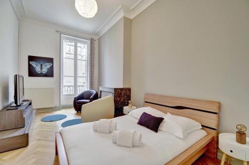 une chambre avec un grand lit blanc et une télévision dans l'établissement L'Impérial - Luxeux appartement dans le Triangle d'Or, à Bordeaux