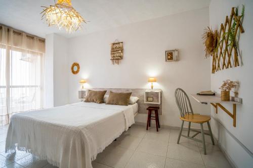 a white bedroom with a bed and a desk at Hotel Los Narejos in Los Alc&aacute;zares